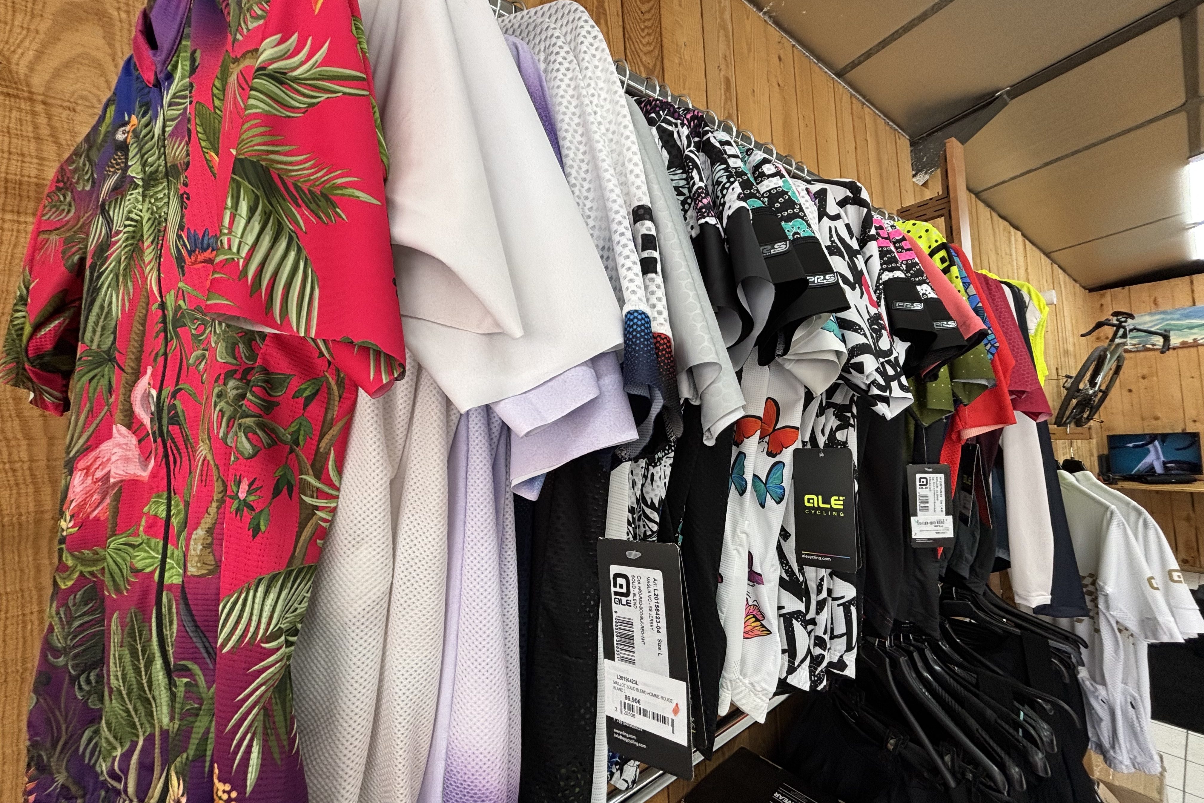 Une étagère présentant une variété de maillots colorés, y compris des motifs floraux, des designs monochromes et des motifs animaliers, dans un magasin de vêtements.