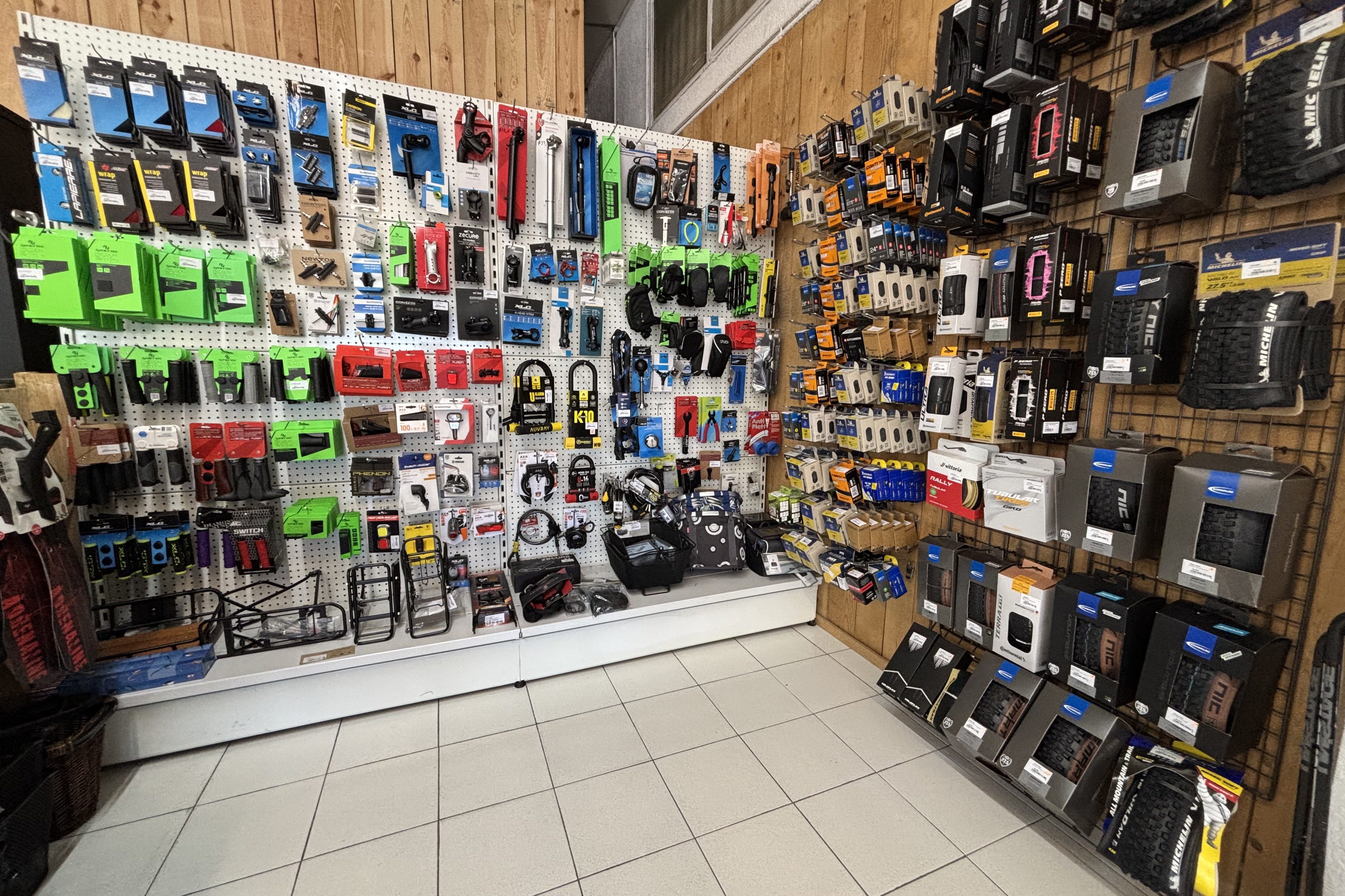 Un mur de magasin rempli d'outils et d'accessoires, y compris des pièces de vélo, des accessoires de jardin et divers équipements de sport.